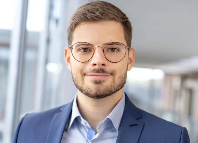 An employee of zeb a man wearing glasses and a suit